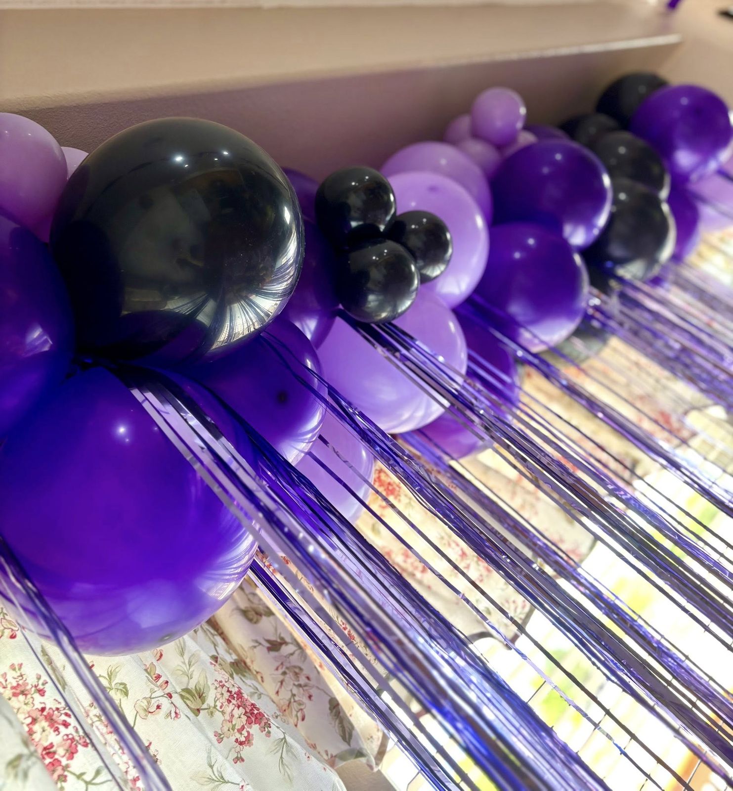 Close-up of a purple and black balloon garland with foil tinsel